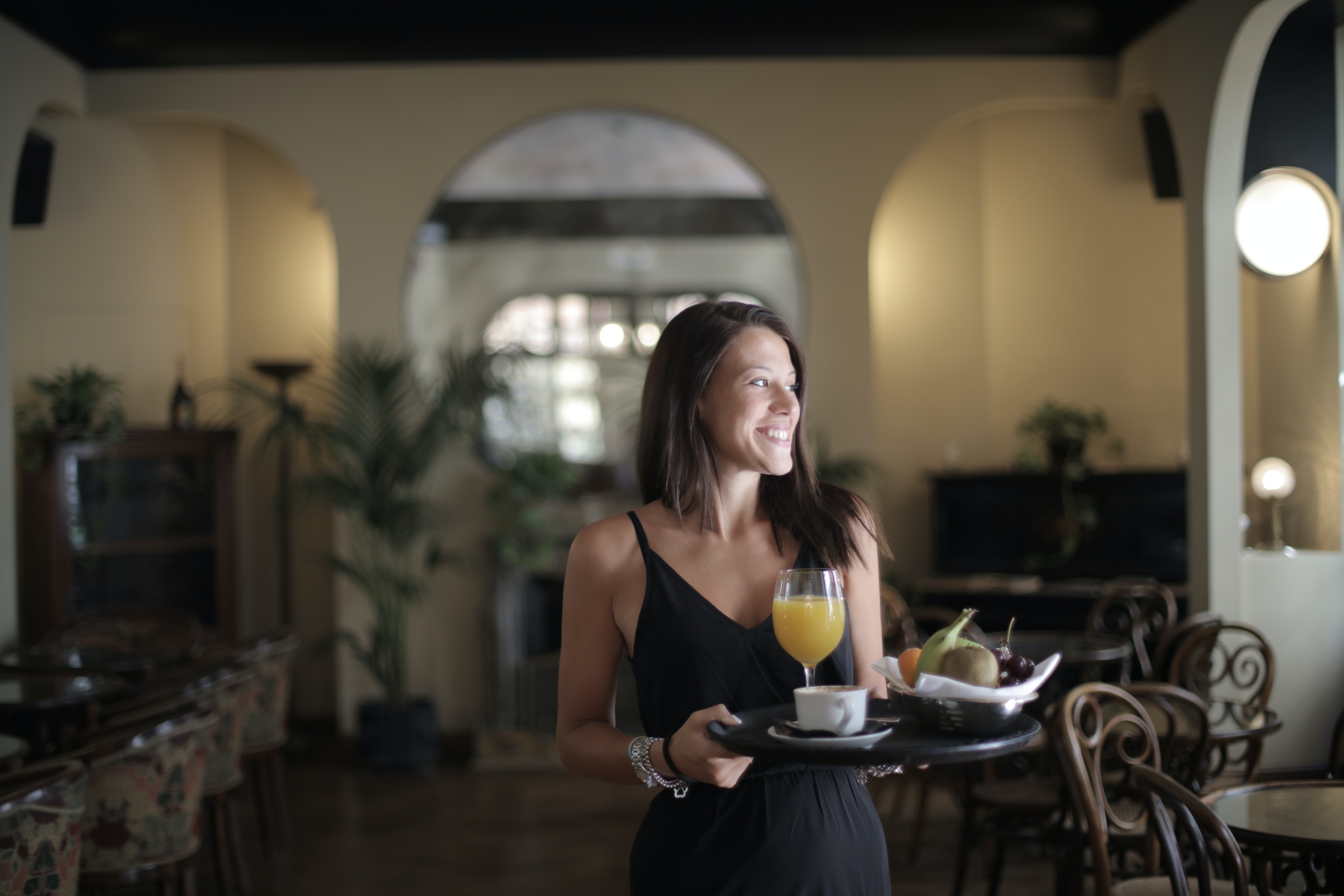 woman holding tray of fruit and coffee in hotel