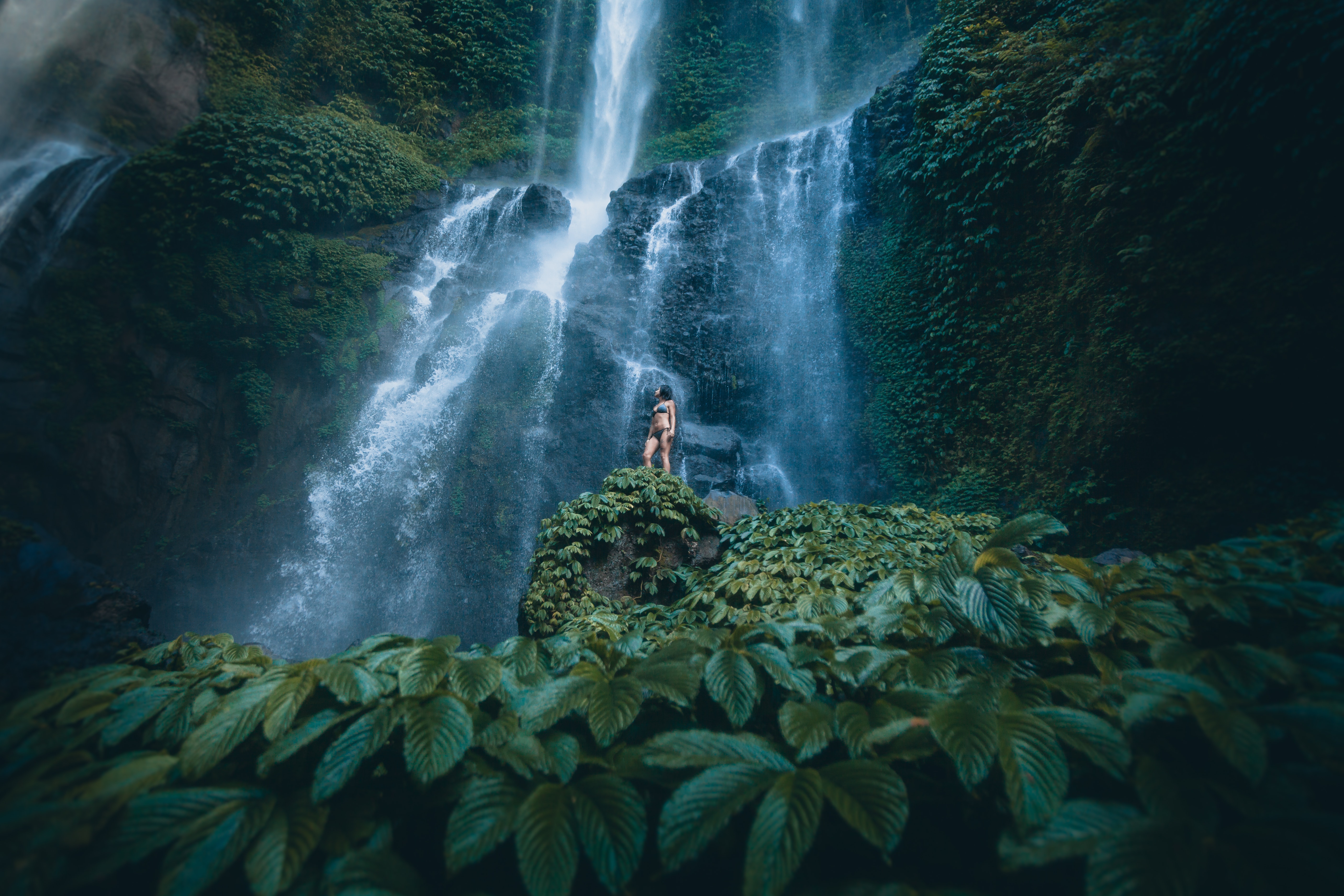 Woman standing underneath waterfall in Bali